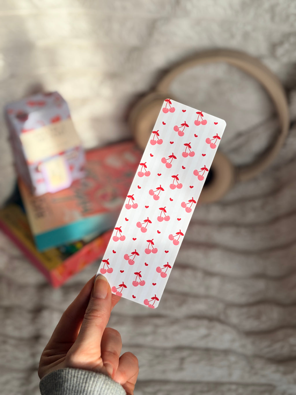 Hand holding a rectangular card with cherry pattern against a blurred background